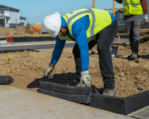 Worker in vest and helmet installs Hercules Eco Block along sidewalk.