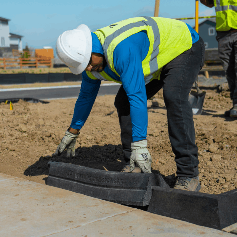 Worker in vest and helmet installs Hercules Eco Block along sidewalk.